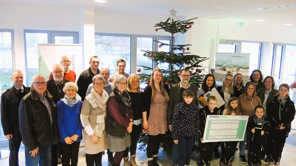 Presentation of cheque for Christmas donation in front of Christmas tree