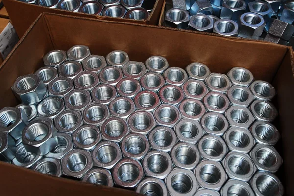 Metallmuttern in großer Anzahl ordentlich in einer Kiste gestapelt.