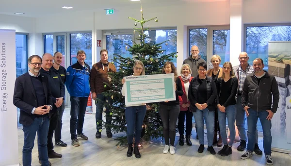 Übergabe Spendenscheck Weihnachtsspende vor Weihnachtsbaum