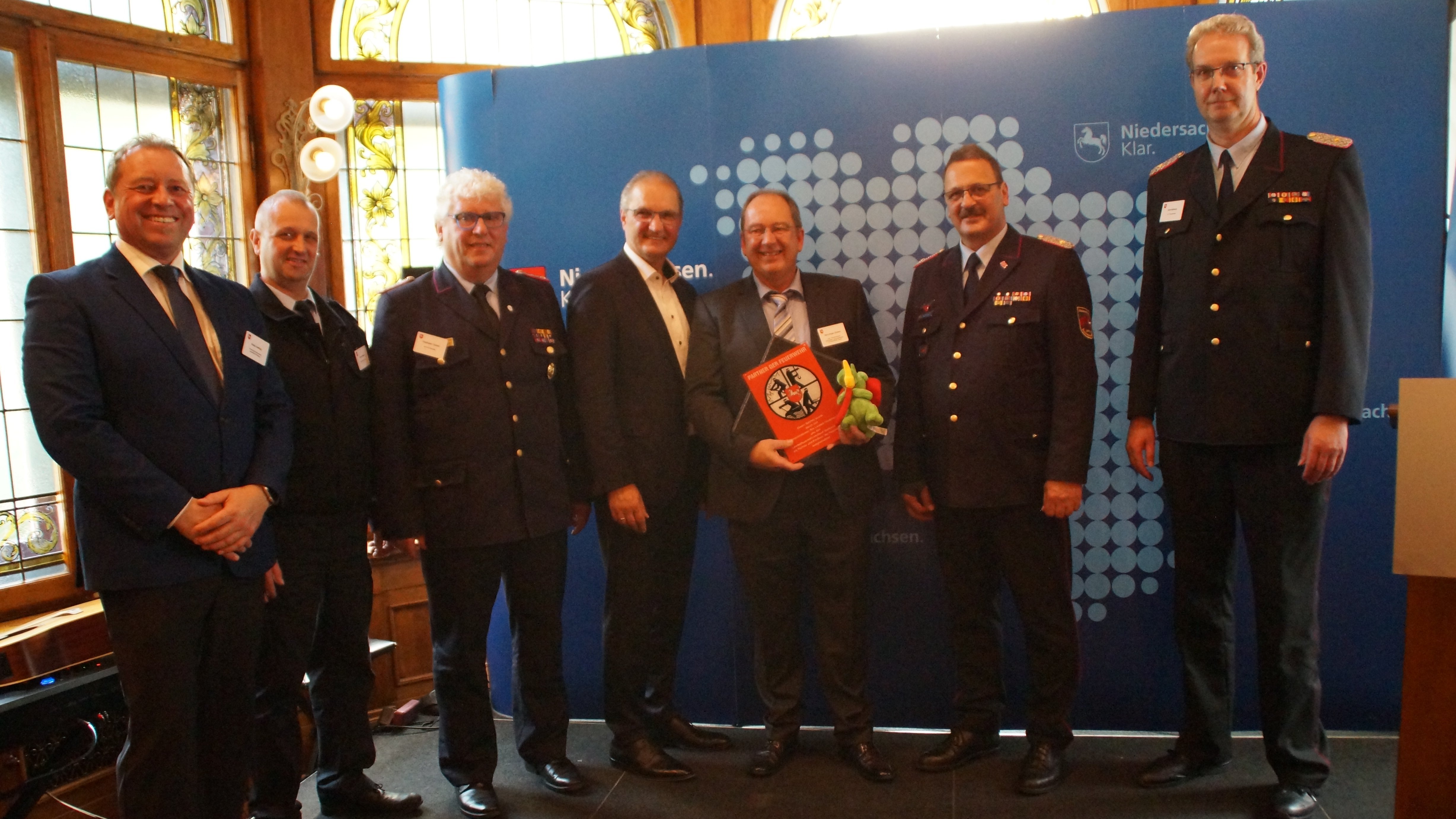 Foto mit den Beteiligten aus dem Landkreis Wittmund: v.l.n.r. Bürgermeister Goetz, Gemeindebrandmeister Schlegel, Kreisbrandmeister
 Tannen, Staatssekretär Stephan Manke, Kurt-Jürgen Grabert/STORAG
 ETZEL, LFV-Präsident Olaf Kapke, LfV-Vizepräsident Gerd Dieken